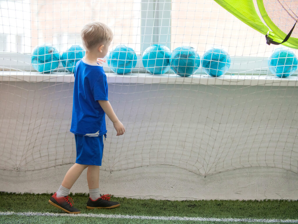Criança observando bolas de futebol azuis