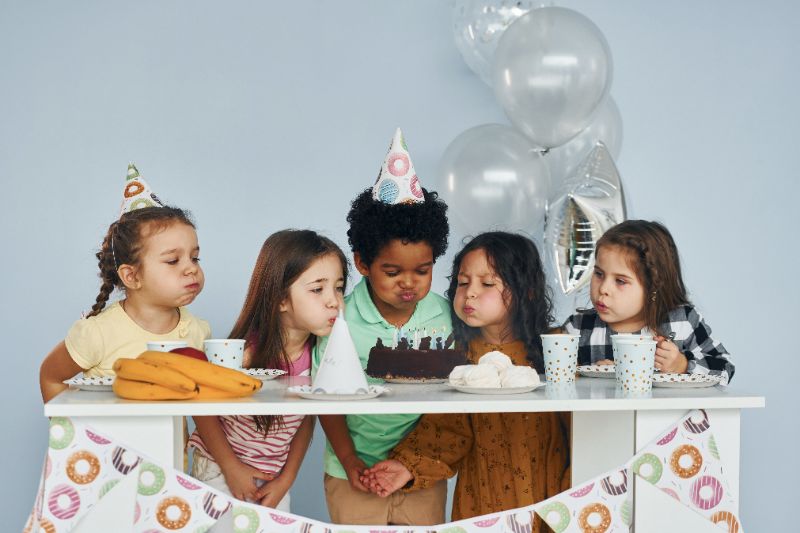 Crianças assoprando vela de bolo de aniversário